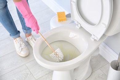 Photo of Woman cleaning toilet bowl in bathroom, closeup