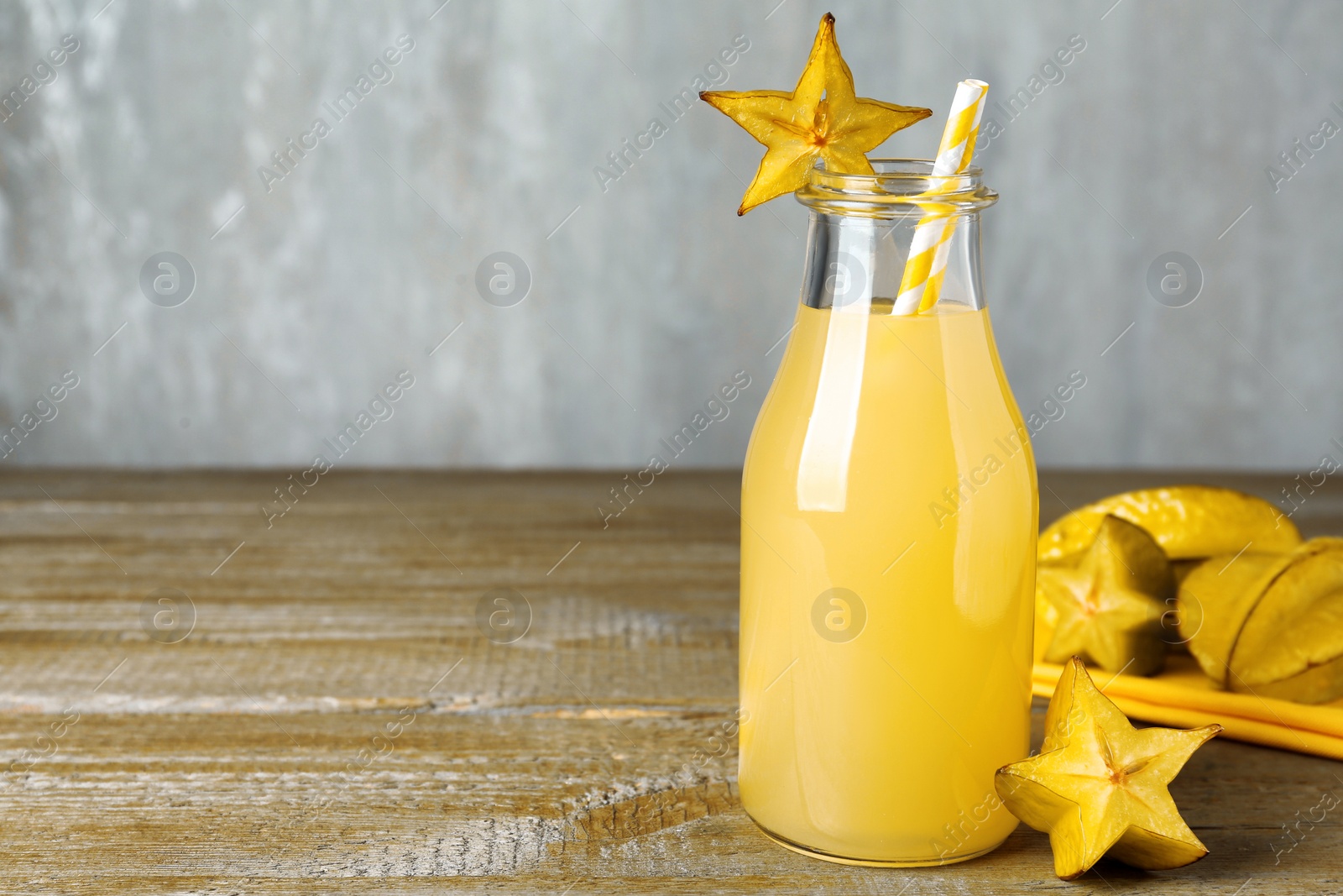 Photo of Delicious carambola juice and fresh fruits on wooden table. Space for text