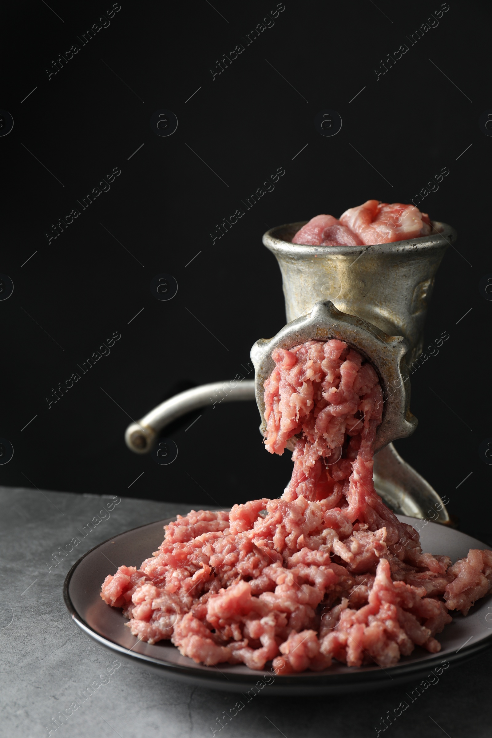 Photo of Manual meat grinder with beef mince on grey table