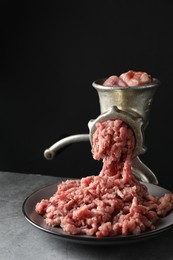 Manual meat grinder with beef mince on grey table