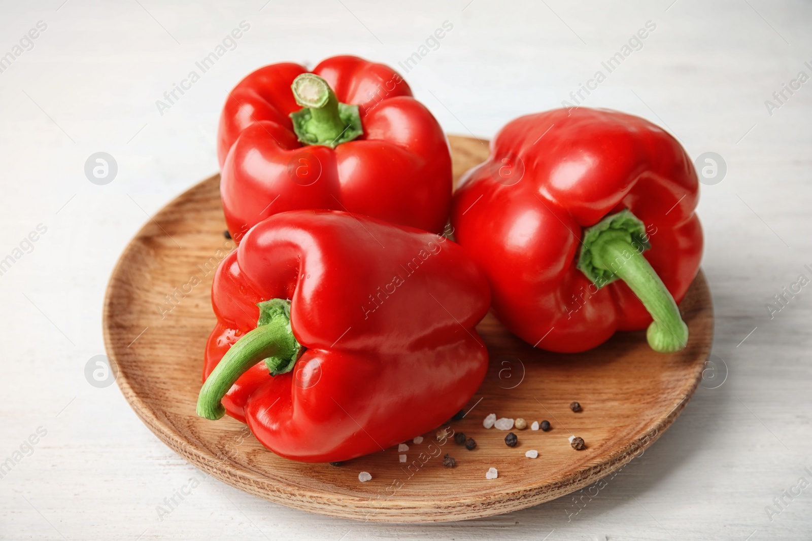 Photo of Plate with ripe paprika peppers on white wooden background