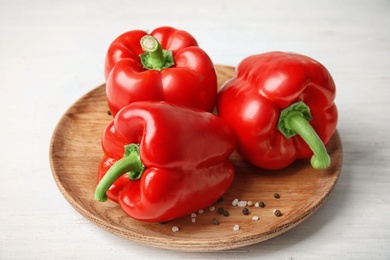 Plate with ripe paprika peppers on white wooden background