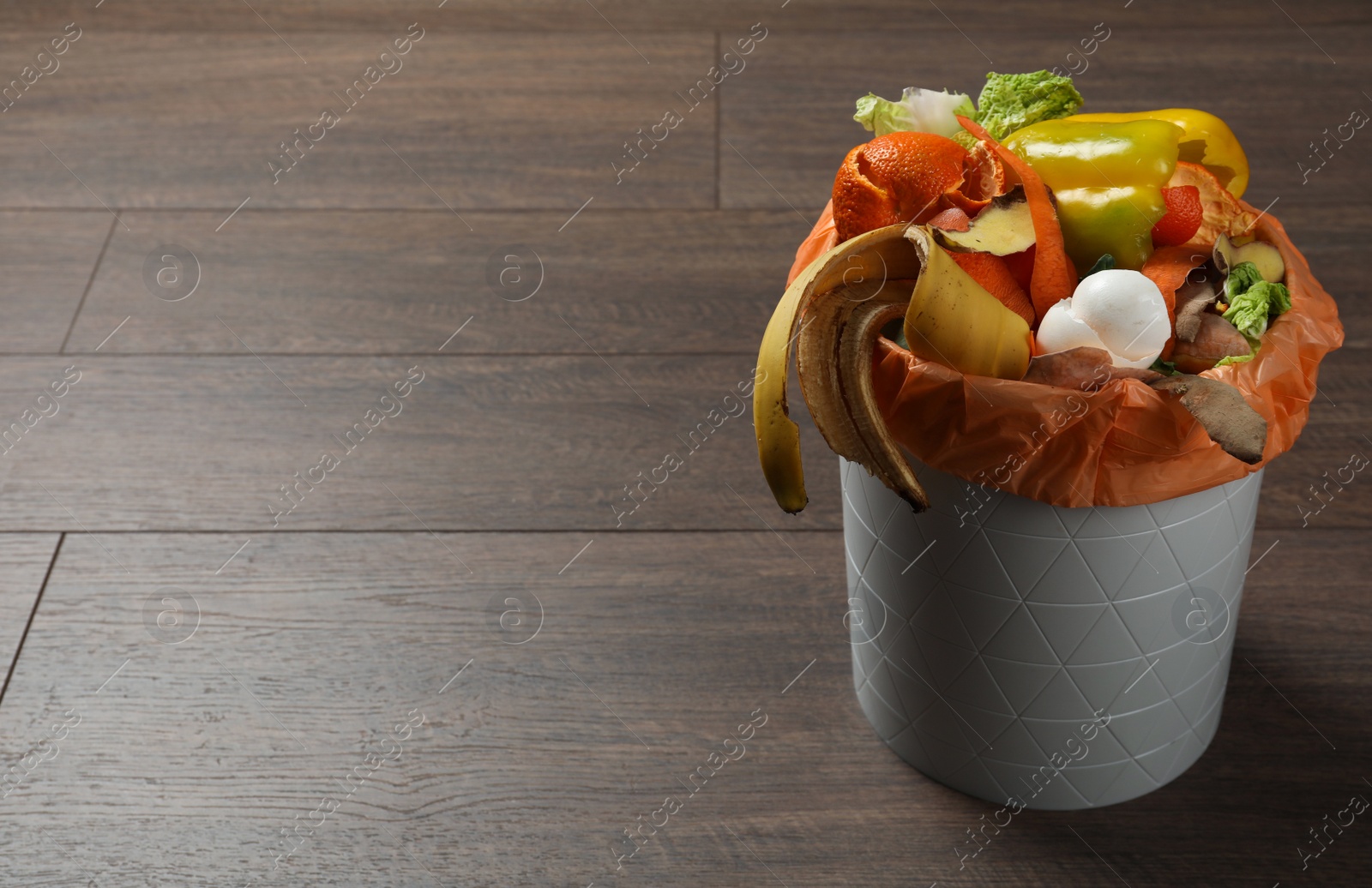 Photo of Trash bin with natural garbage on wooden background, space for text. Composting of organic waste