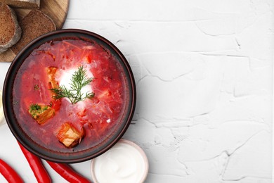 Photo of Tasty borscht with sour cream in bowl served on white textured table, flat lay. Space for text
