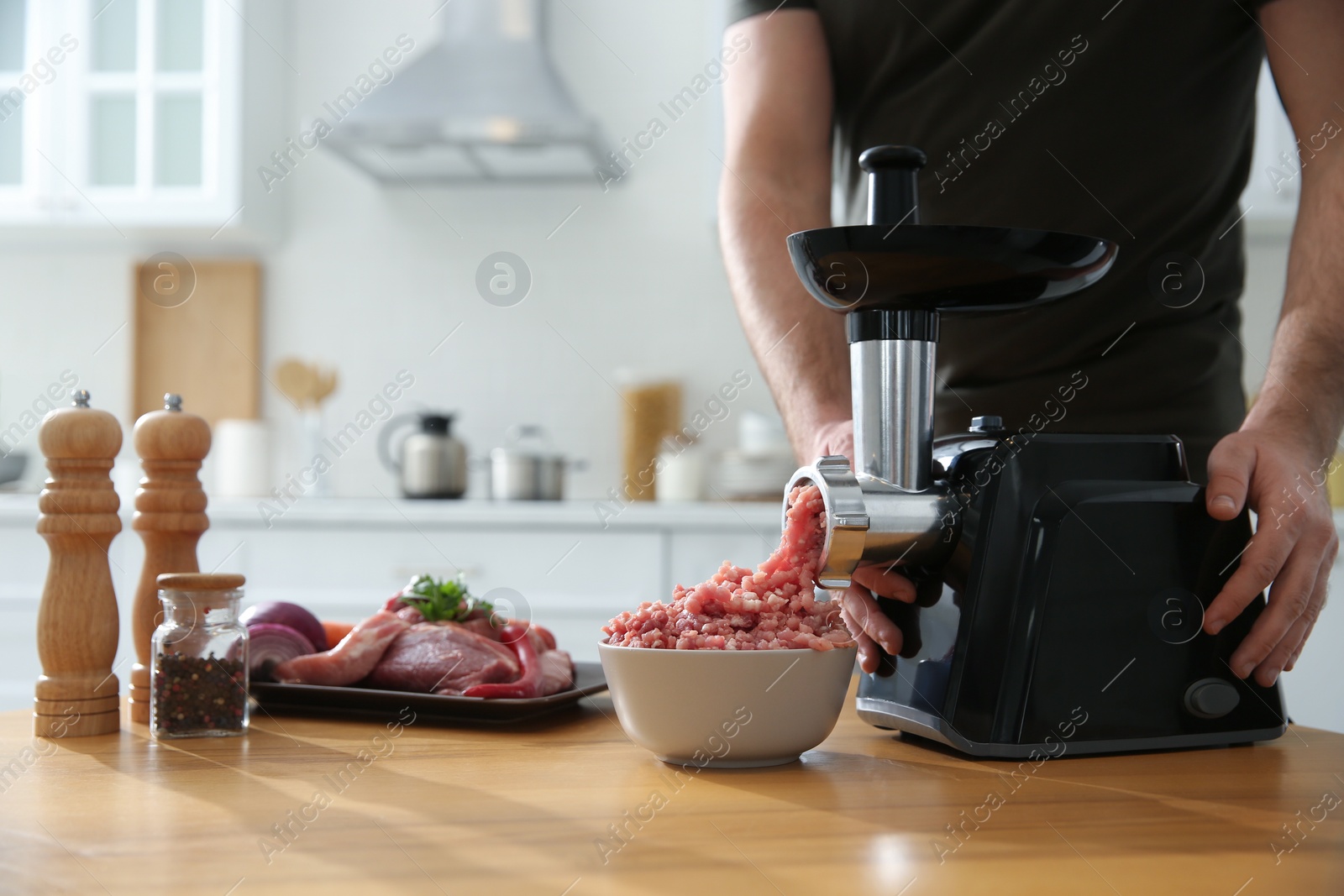 Photo of Man using modern meat grinder in kitchen, closeup