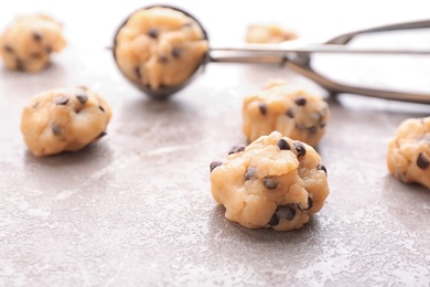 Photo of Cookie dough with chocolate chips and scoop on light background