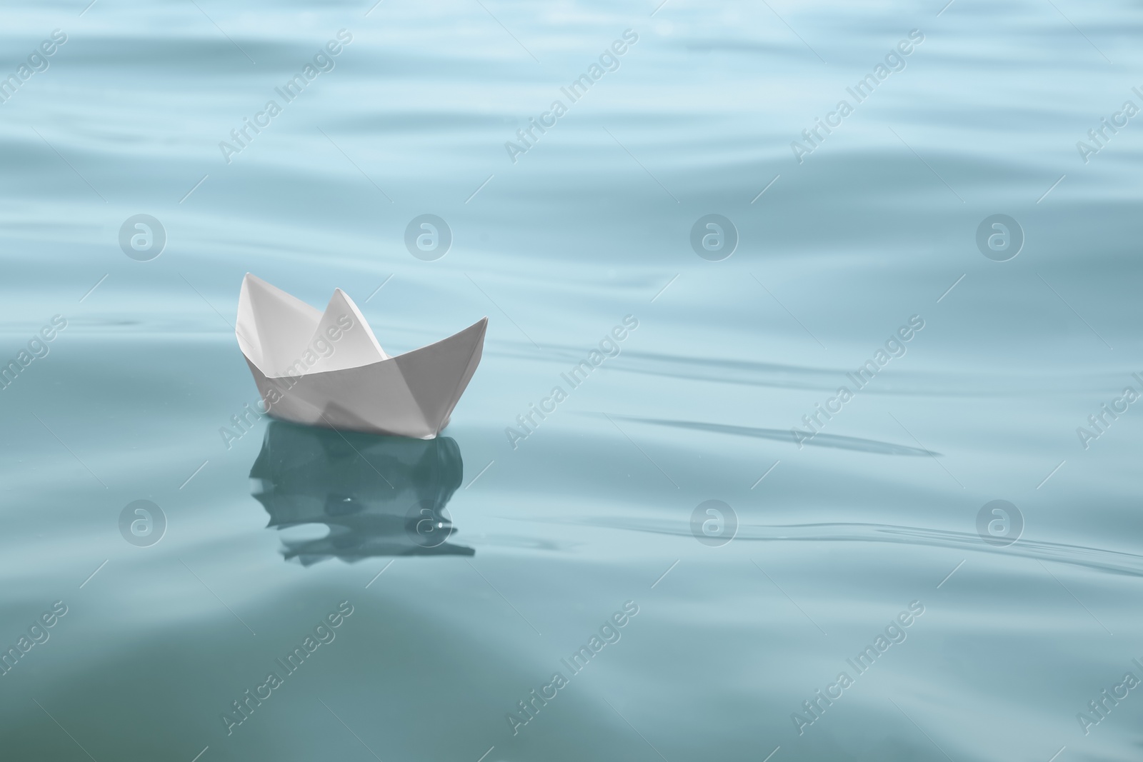 Photo of White paper boat floating on water surface, space for text