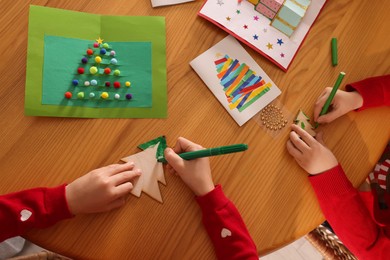 Photo of Little children making Christmas crafts at wooden table, top view