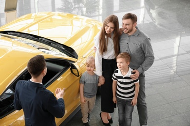 Young family with salesman in car salon