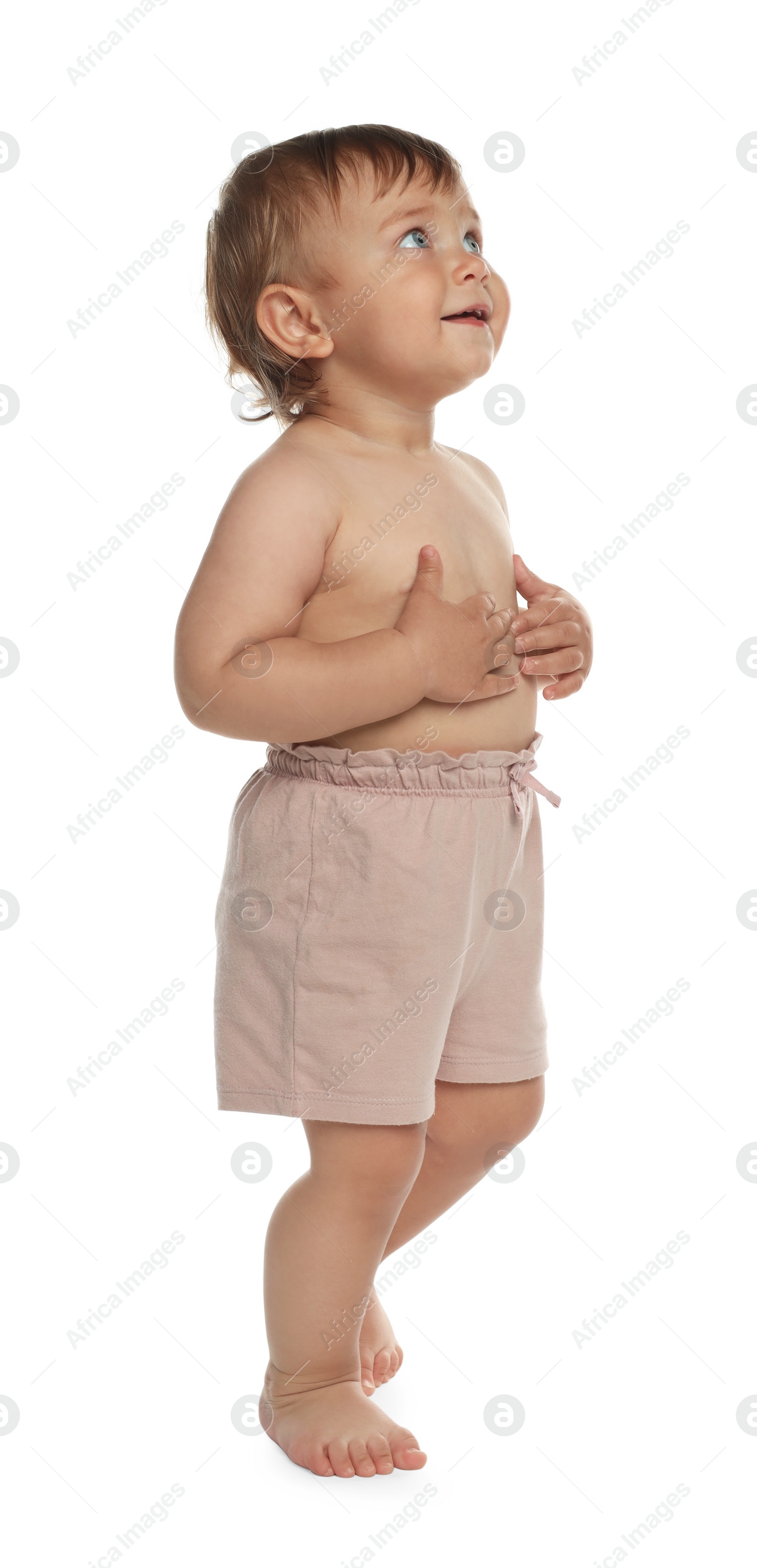 Photo of Cute baby in shorts learning to walk on white background