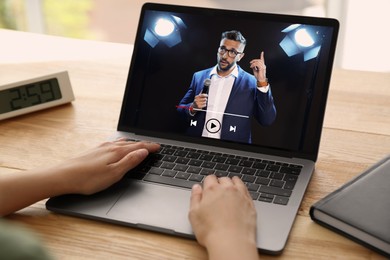 Image of Woman watching performance of motivational speaker on laptop at wooden table, closeup