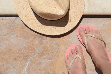 Woman wearing stylish flip flops near hat outdoors, top view