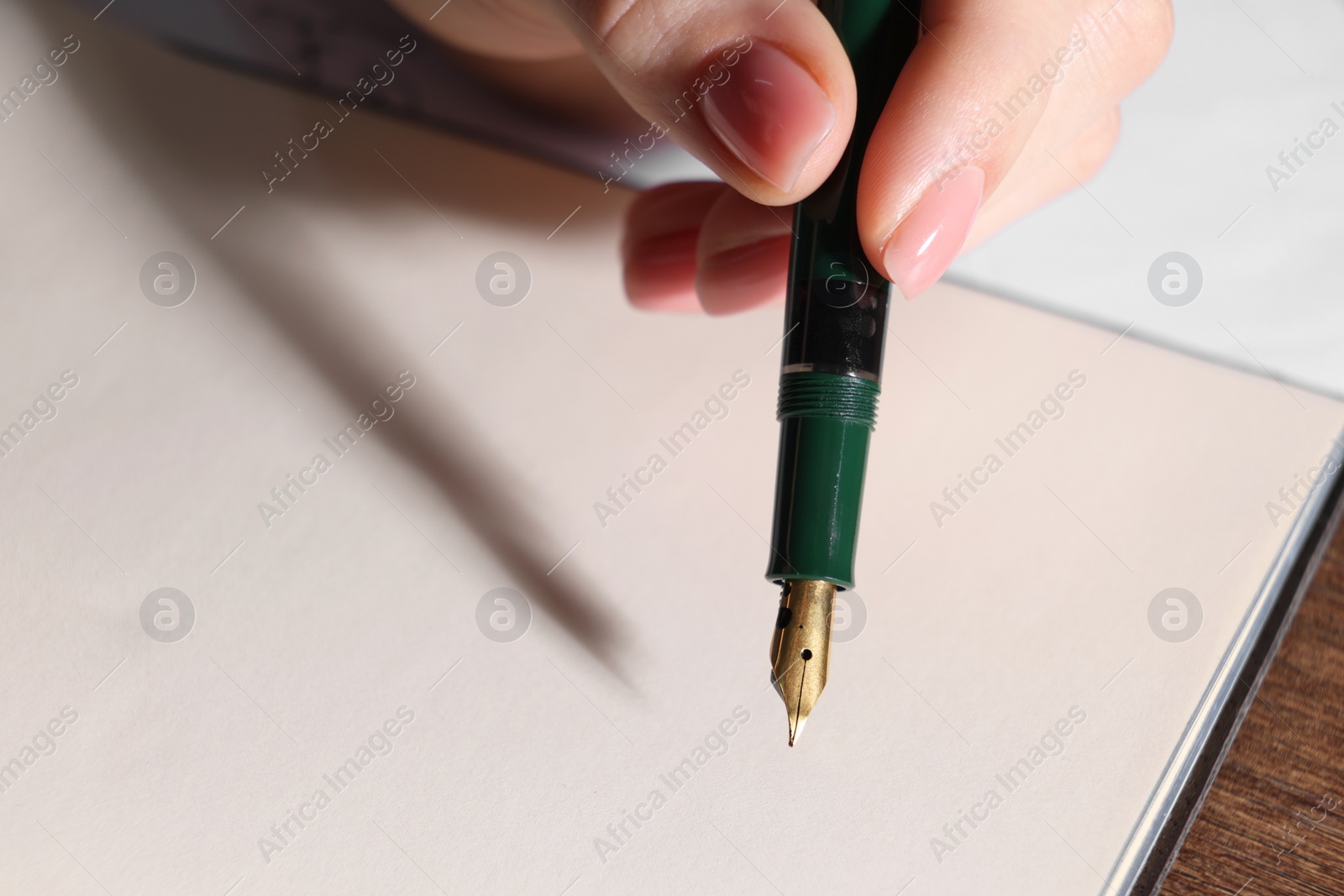 Photo of Woman writing with fountain pen at table, closeup