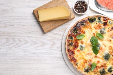 Delicious homemade quiche and ingredients on wooden table, flat lay. Space for text