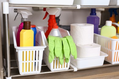 Open under sink cabinet with different cleaning supplies in kitchen