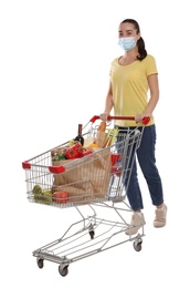Photo of Woman with protective mask and shopping cart full of groceries on white background