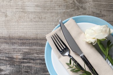 Stylish table setting with cutlery and flowers on wooden background, top view