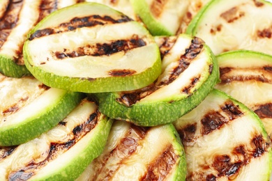 Photo of Delicious grilled zucchini slices as background, closeup view