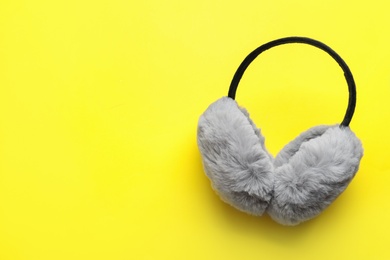 Stylish winter earmuffs on yellow background, top view. Space for text