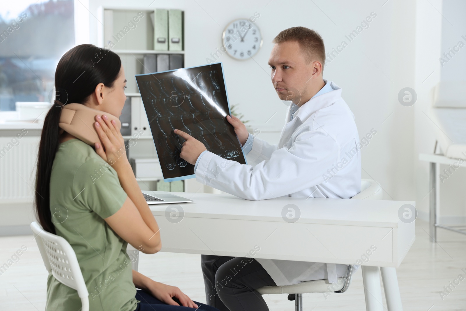 Photo of Doctor with neck MRI image consulting patient in clinic