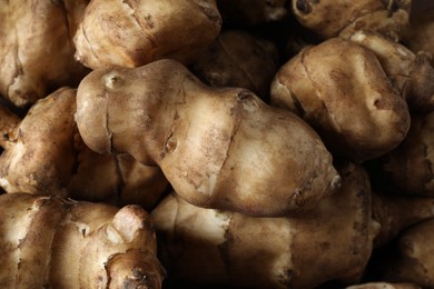 Photo of Many fresh Jerusalem artichokes as background, closeup