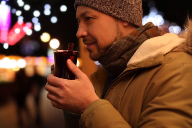 Photo of Happy man with mulled wine at winter fair