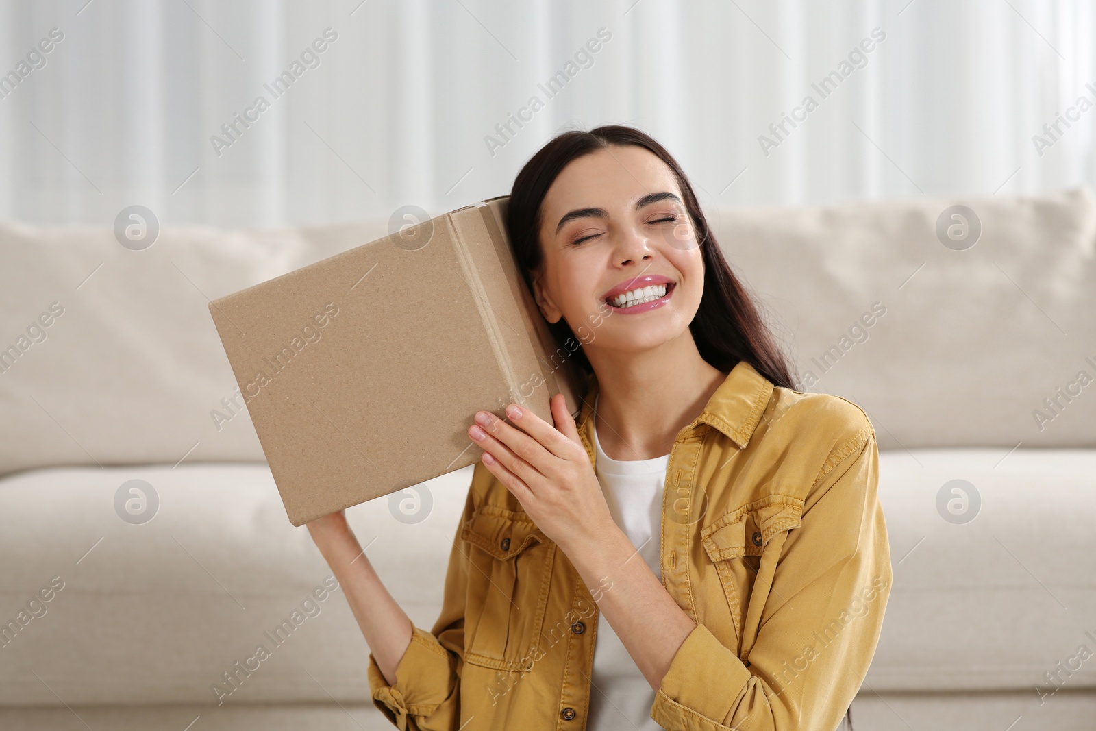 Photo of Happy young woman with parcel at home. Internet shopping