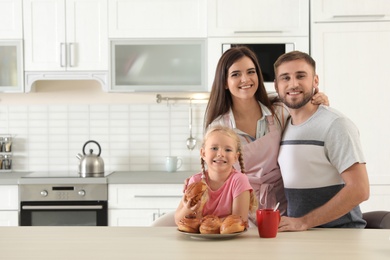 Photo of Happy family with freshly oven baked buns at table in kitchen. Space for text