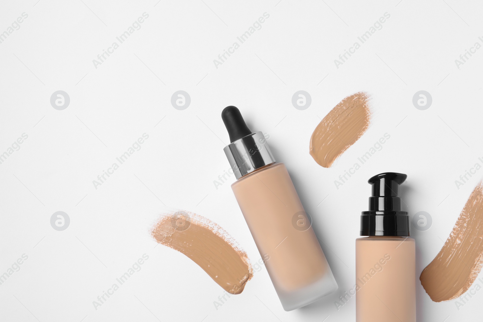 Photo of Liquid foundations and swatches on white background, flat lay. Space for text