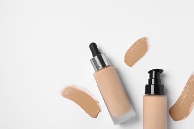 Photo of Liquid foundations and swatches on white background, flat lay. Space for text