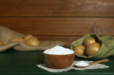 Starch and fresh raw potatoes on green wooden table. Space for text