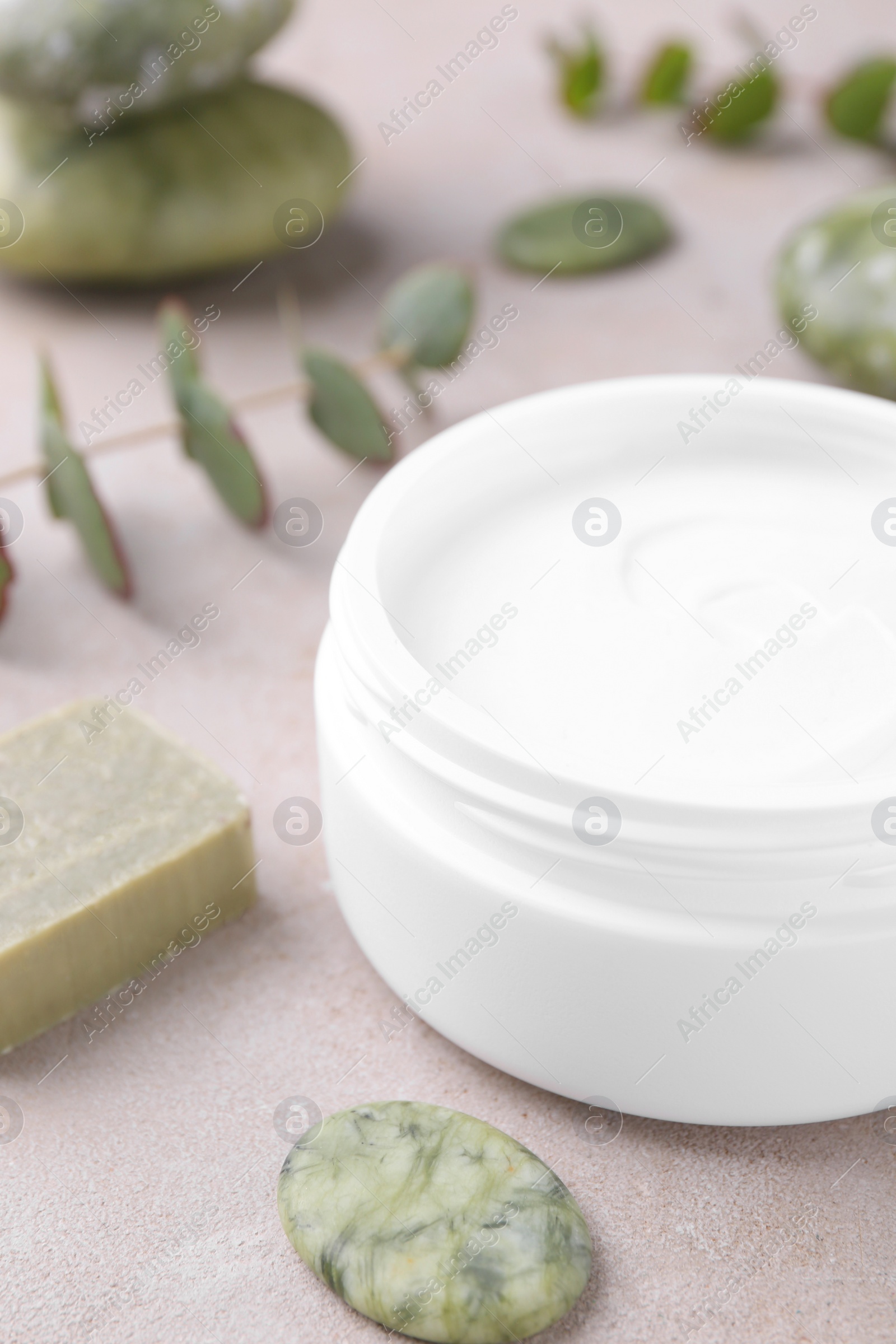 Photo of Jar of cream, soap and spa stone on light textured table, closeup. Body care product