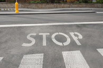 White sign STOP written on asphalt road outdoors