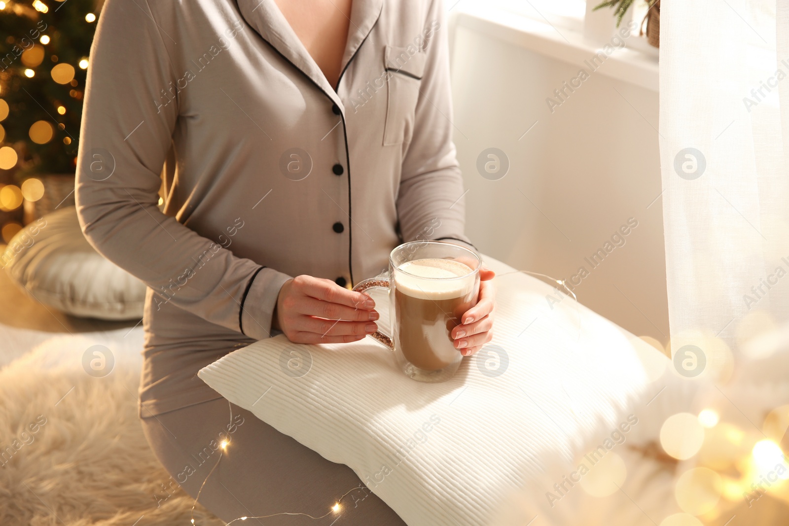 Photo of Woman holding cup with hot drink indoors, closeup