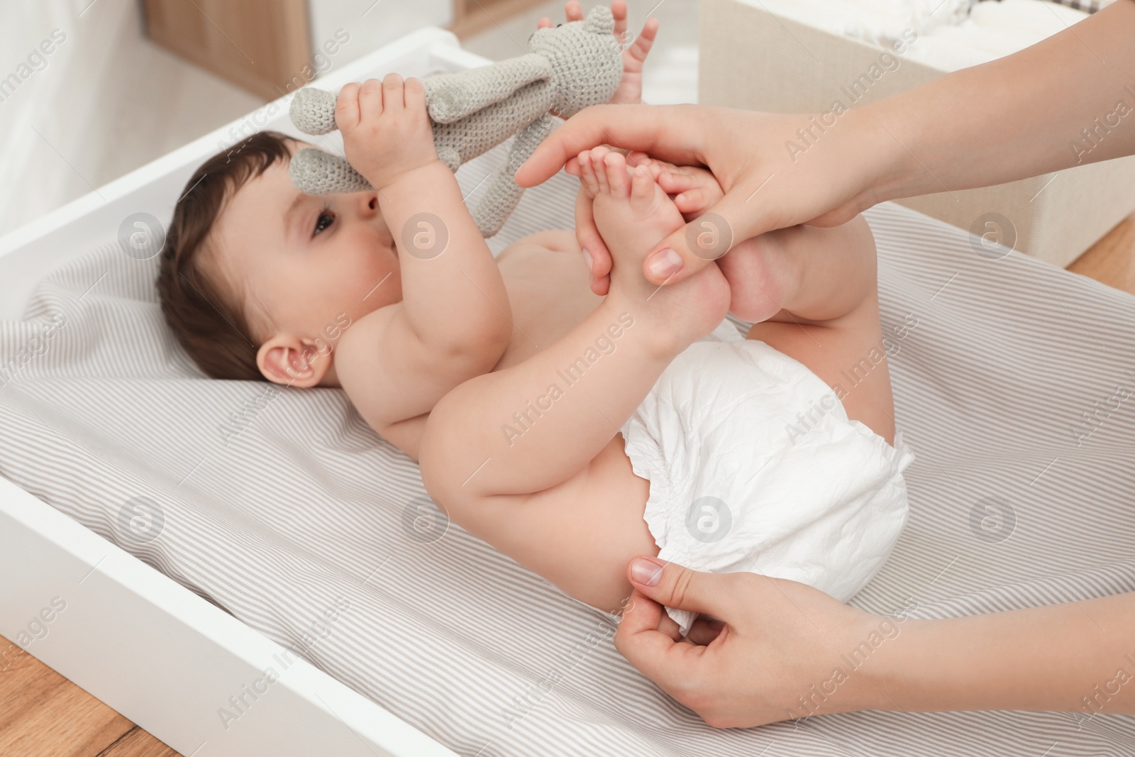 Photo of Mother changing baby's diaper on table at home, closeup