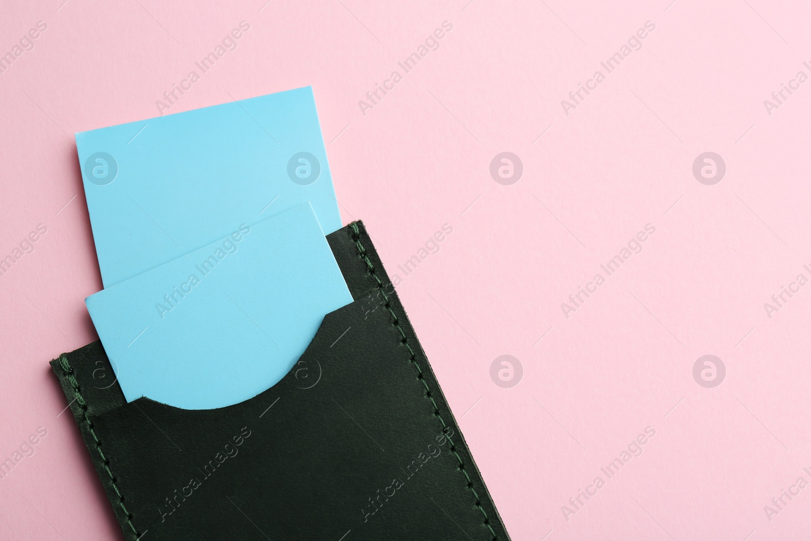 Photo of Leather business card holder with blank cards on pink background, top view. Space for text