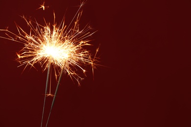Photo of Bright burning sparklers on red background, closeup. Space for text
