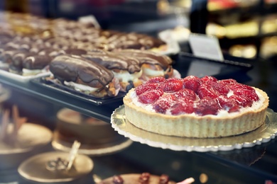 Different delicious cakes on display in cafe, view through window