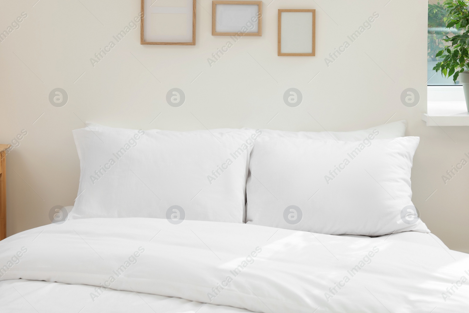 Photo of White soft pillows on cozy bed in room