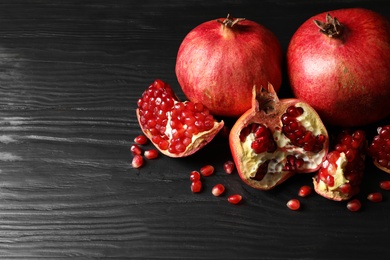 Photo of Ripe pomegranates on dark wooden background. Space for text