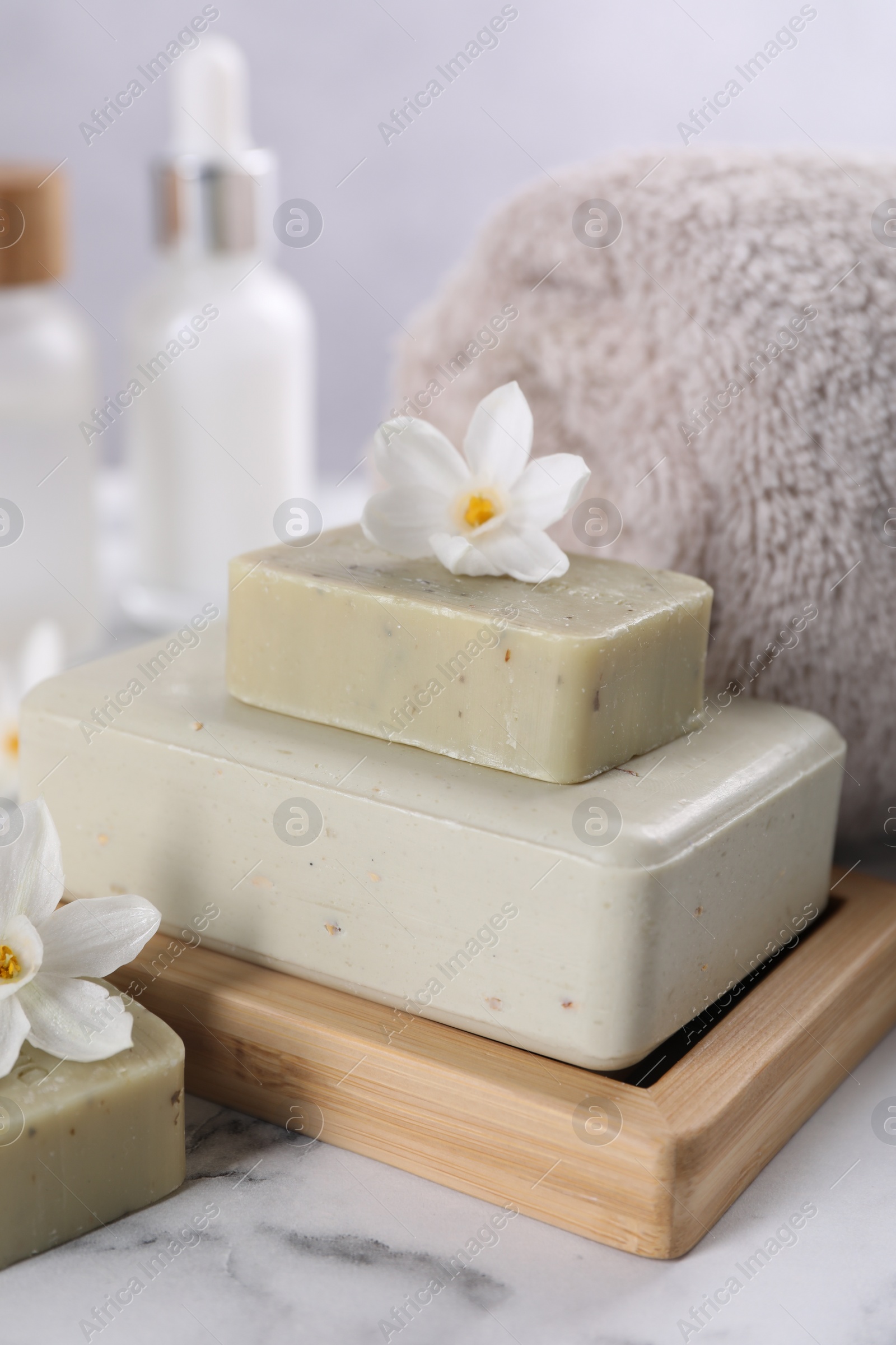 Photo of Spa composition with soap, flowers and towel on white marble table