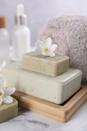 Photo of Spa composition with soap, flowers and towel on white marble table