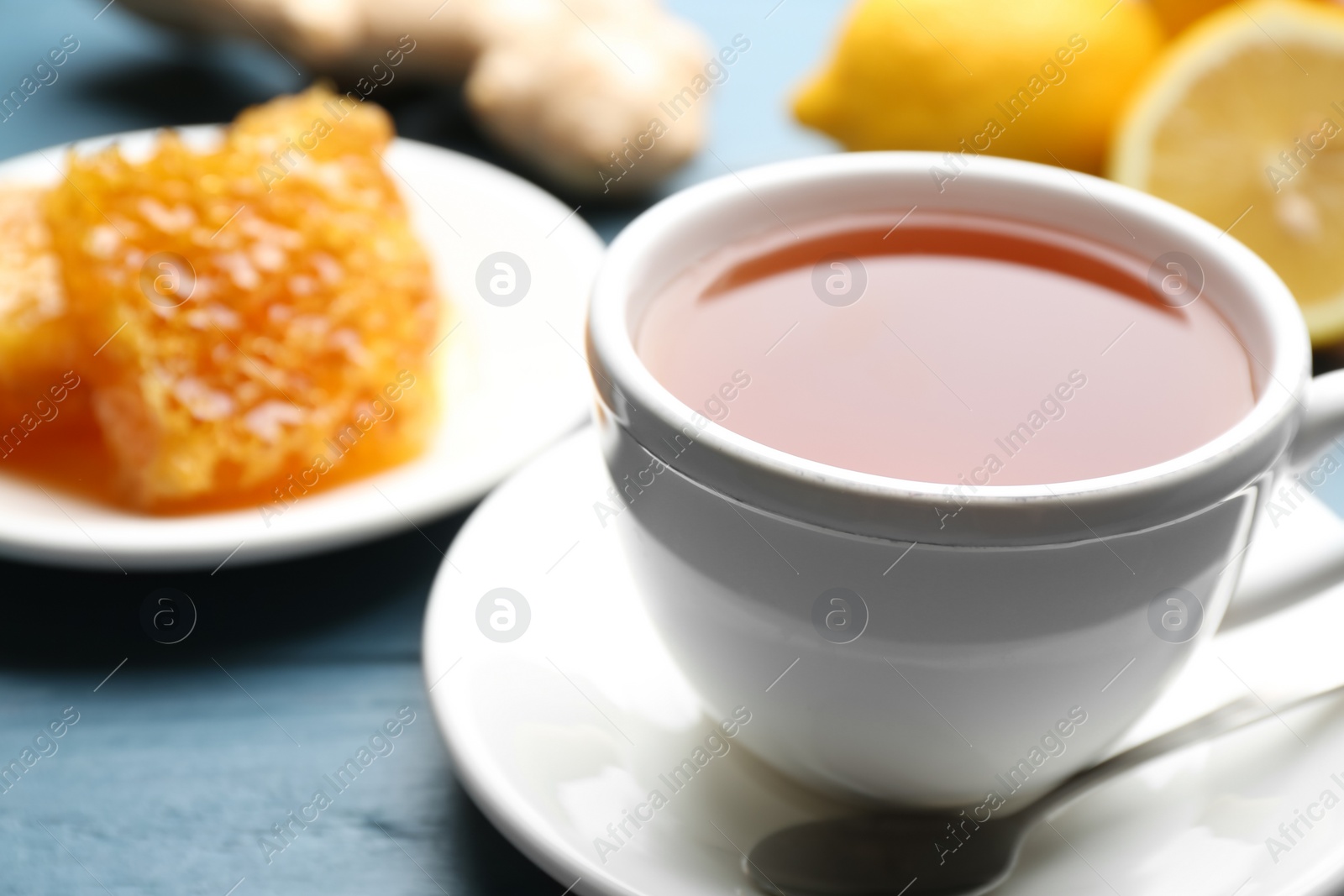 Photo of Tea with honey and lemon on blue wooden table, closeup