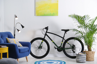 Modern bicycle and comfortable armchair in stylish living room interior