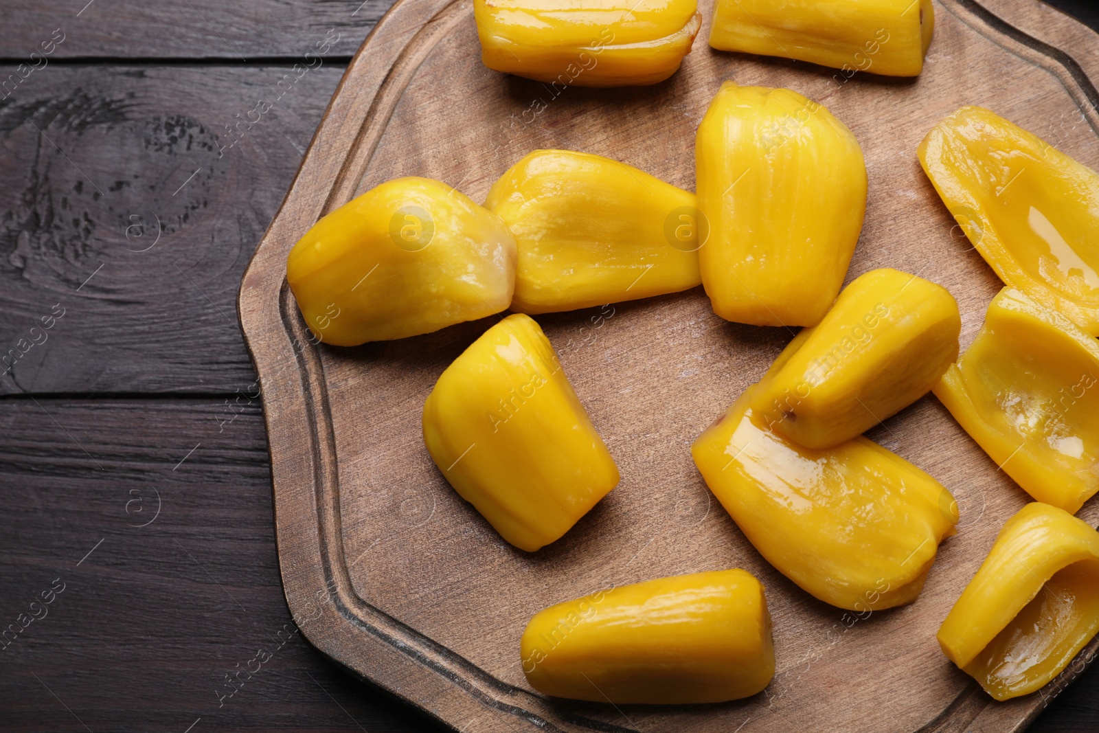 Photo of Fresh exotic jackfruit bulbs on black wooden table, flat lay