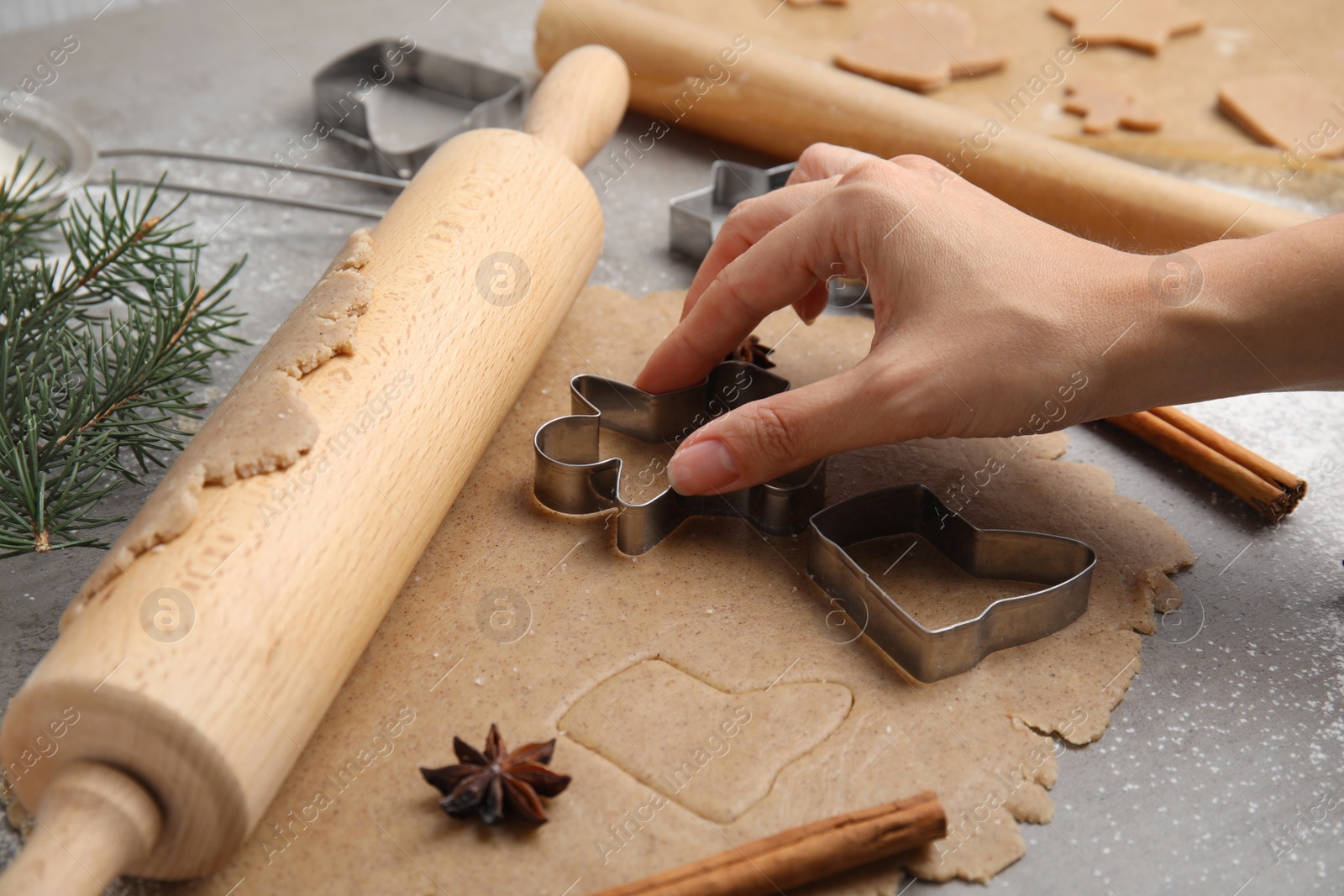 Photo of Woman making gingerbread man with cutter at table, closeup. Homemade Christmas biscuits