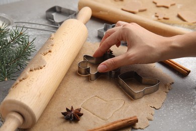 Woman making gingerbread man with cutter at table, closeup. Homemade Christmas biscuits