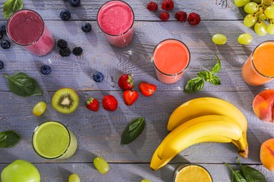 Photo of Many different delicious smoothies and ingredients on grey wooden table, flat lay
