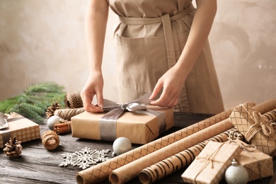 Photo of Woman wrapping Christmas gift at wooden table