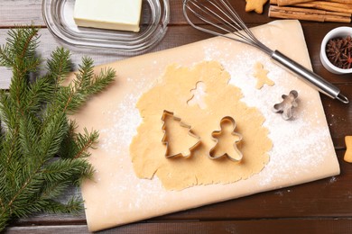 Photo of Making Christmas cookies. Flat lay composition with cutters and raw dough on wooden table